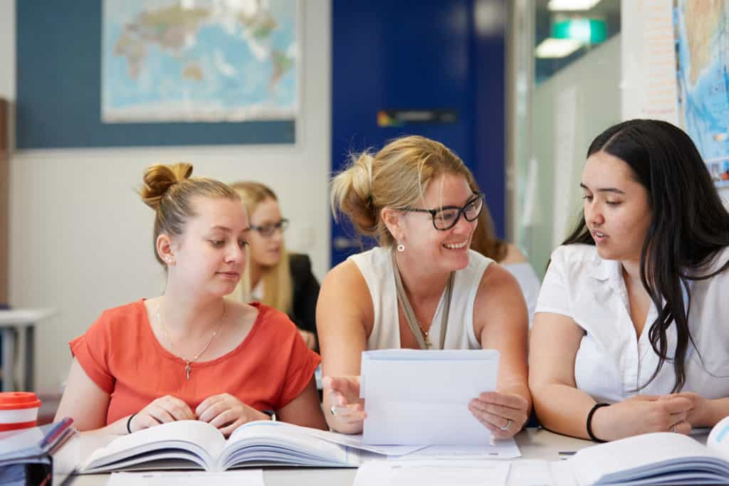 Business trainer helps young female students in a classroom at Centacare West Perth.