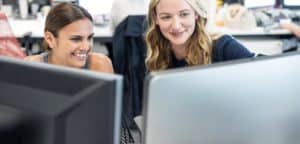 Young women working in an office looking at a computer.
